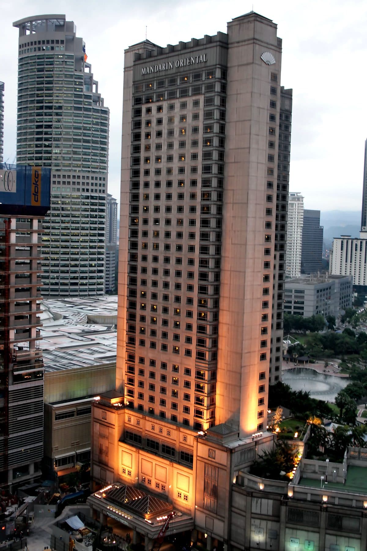 The Mandarin Oriental, Kuala Lumpur tower at dusk, its name lit near the top and its base floodlit