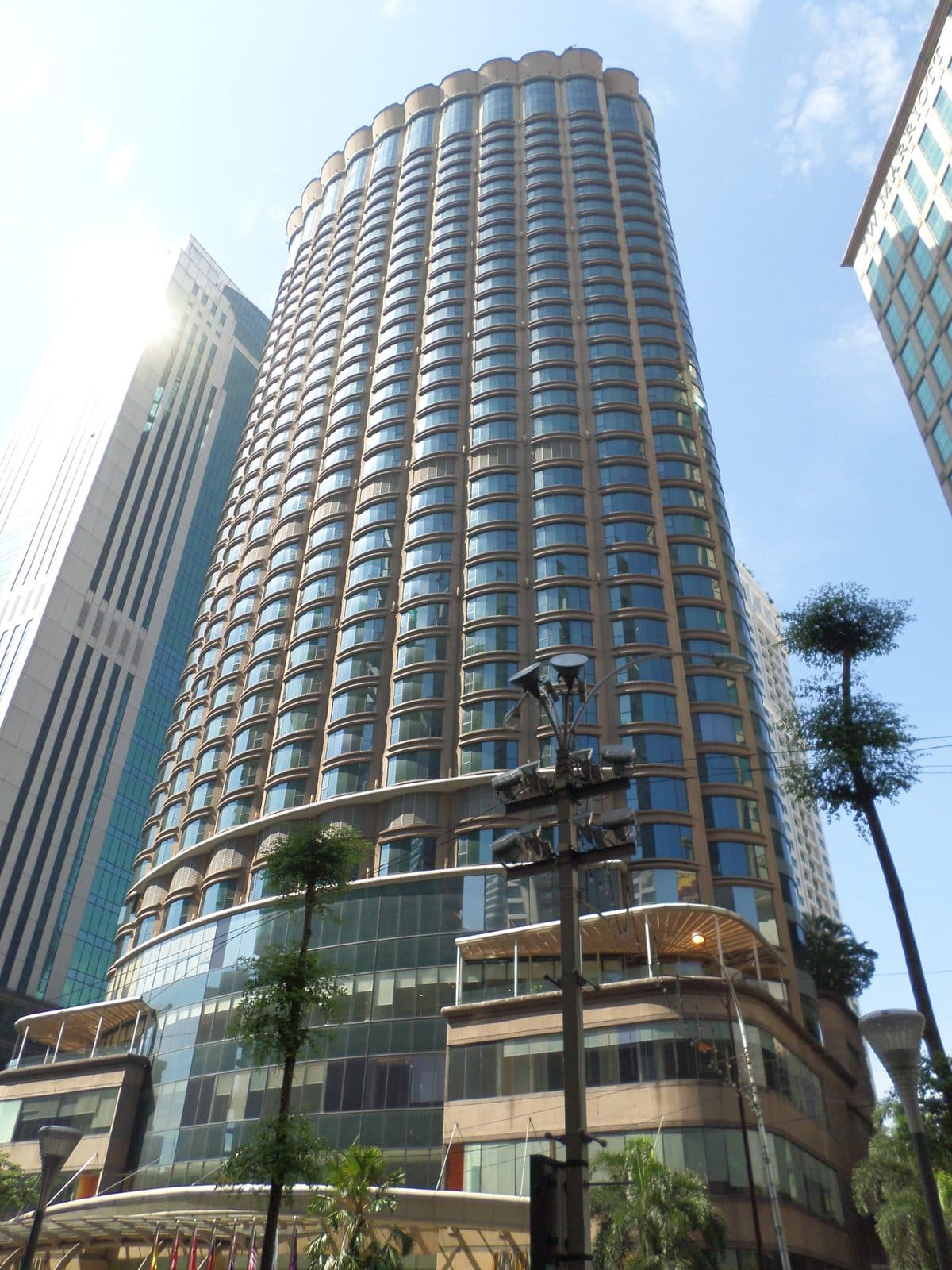 The rounded glass tower of The Westin Kuala Lumpur, seen from the street below on a sunny day