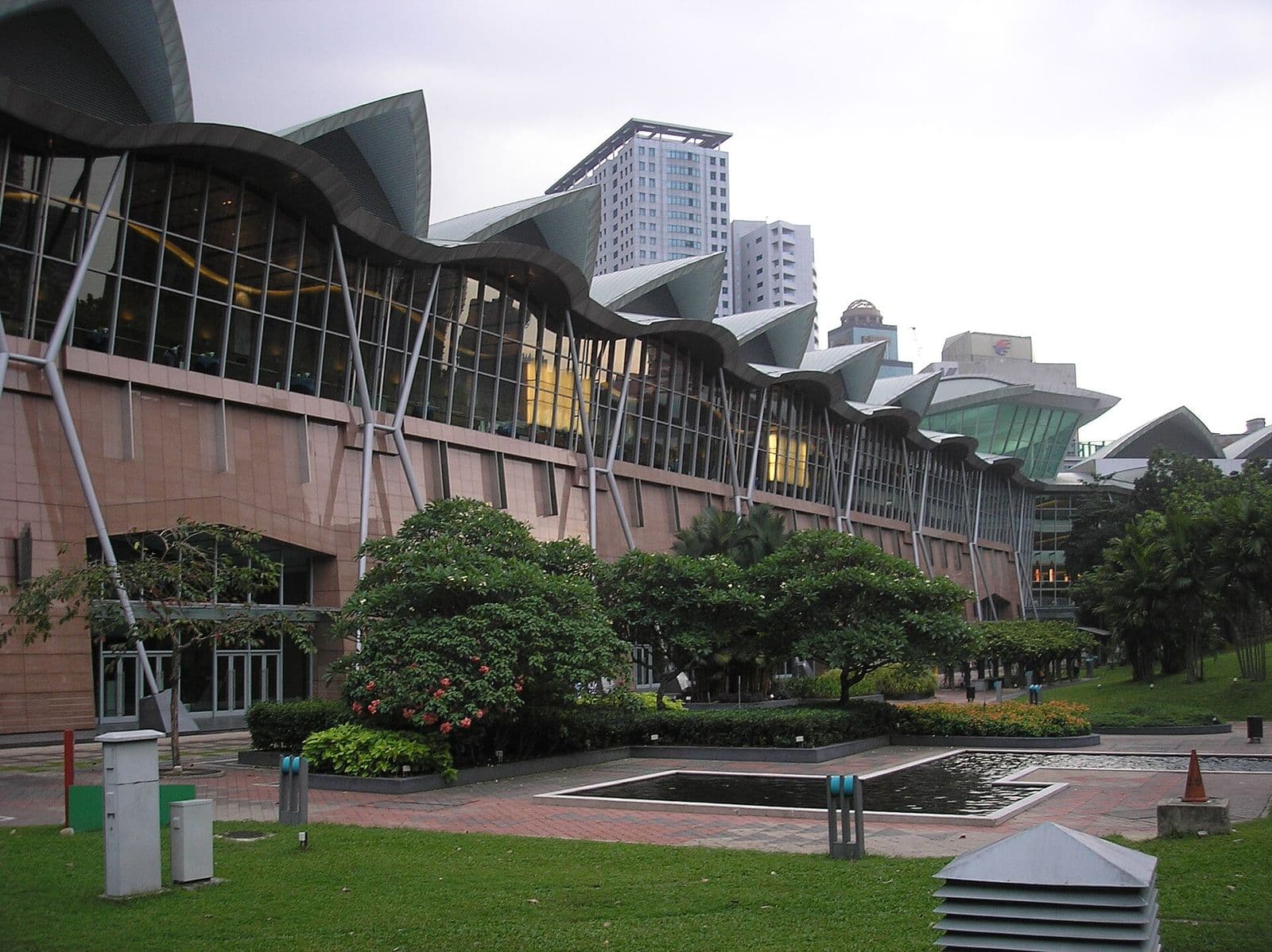 The glass and steel facade of the Kuala Lumpur Convention Centre beside KLCC Park