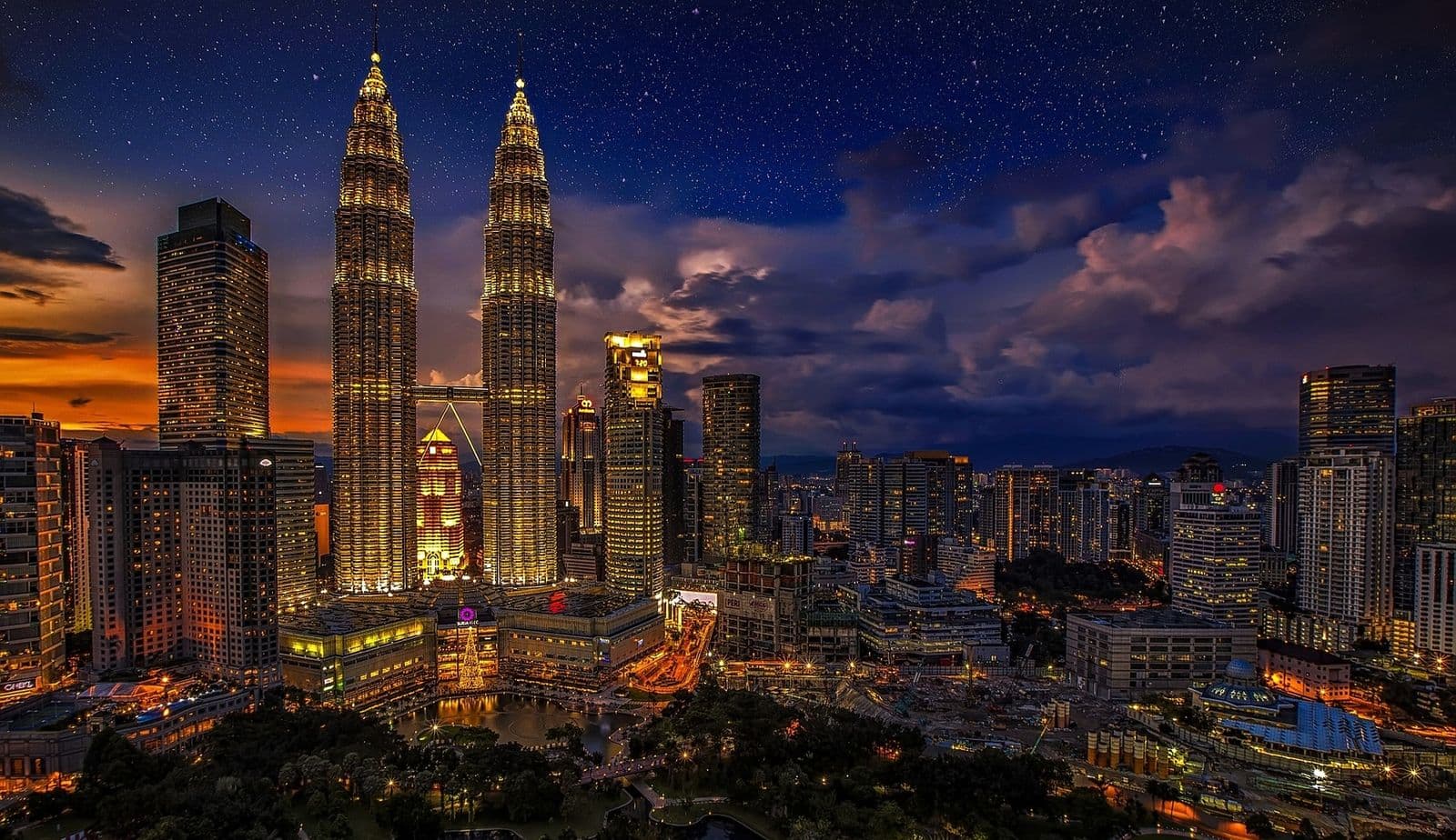 Kuala Lumpur's skyline at dusk, with the Petronas Twin Towers lit up above the city